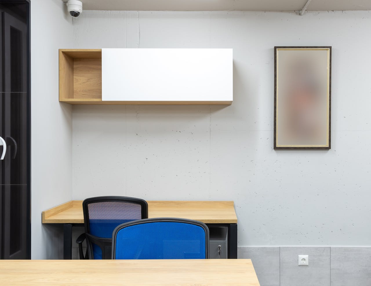 hero-img-01 Wooden tables and blue office chairs placed in modern workplace with shelves on wall