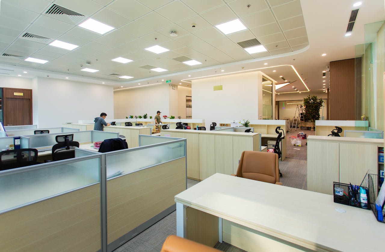 about-01 Bright and spacious office interior featuring open-plan cubicles, modern furniture, and ceiling lights.